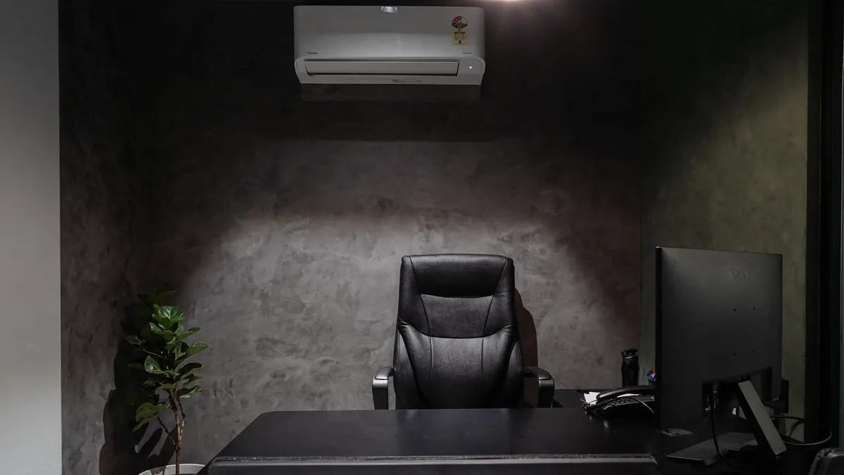 Office space with a wall-mounted air conditioning unit above a desk and seating area