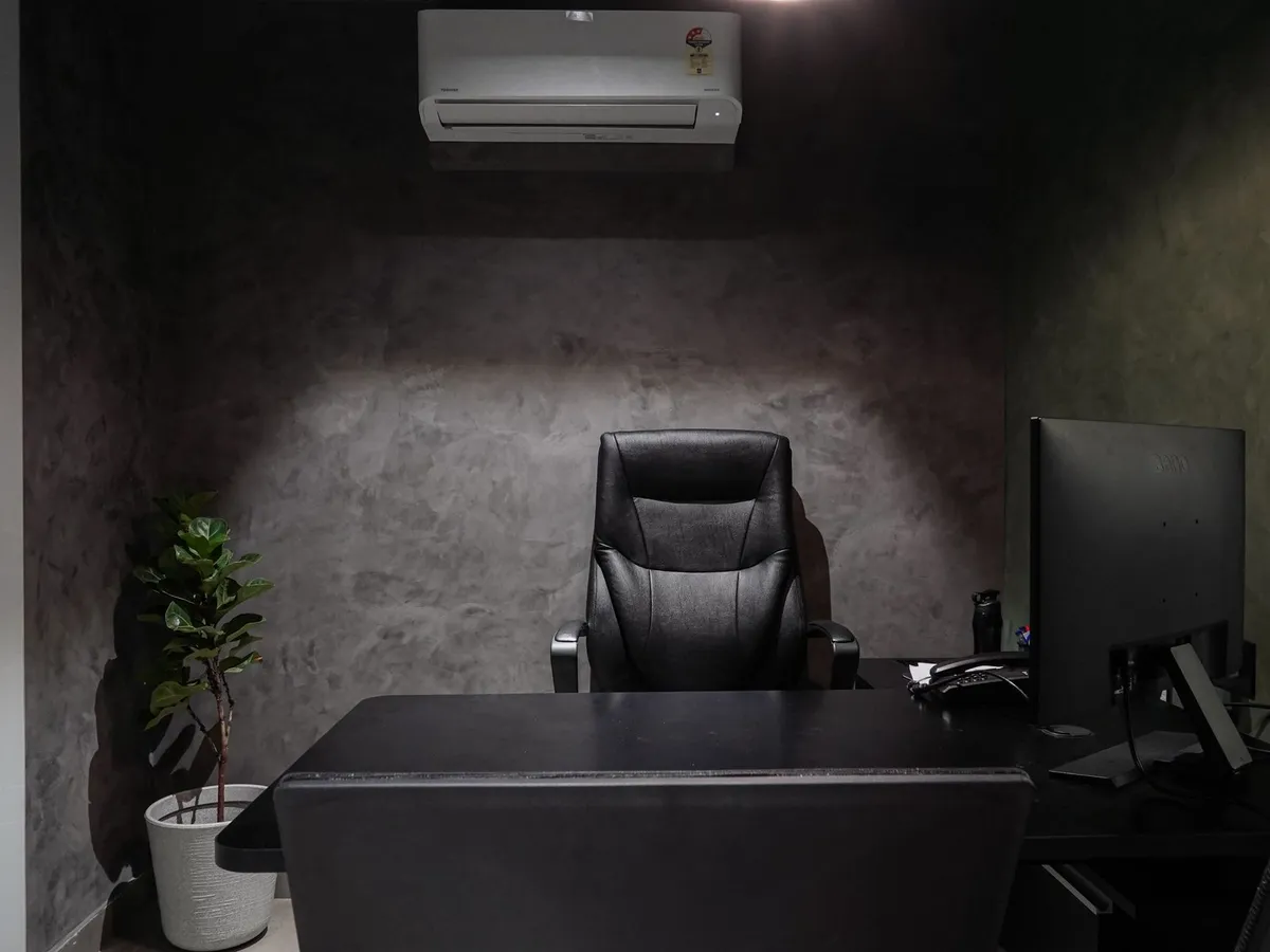 Office space with a wall-mounted air conditioning unit above a desk and seating area
